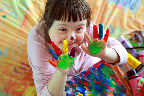 Criança com síndrome de Down sorrindo durante atividade de pintura com as mãos